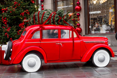 The concept of delivering goods. A Christmas tree is installed on the roof of a vintage red Christmas car. Decorated New Year's Moscow.の写真素材