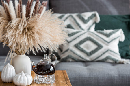 A cozy home-made autumn composition. Still life. A bouquet of dried pampas grass in a vase, white...