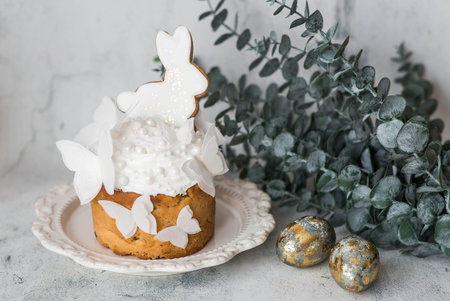 Stylish Easter still life. Easter cake with a white rabbit and butterflies, Easter eggs with gold...