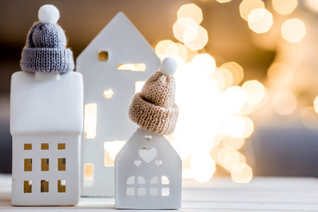 New Year 2026. Models of houses, wearing winter hats with pompoms. Winter. Insulating the house,...