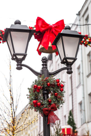 New Year's Eve card 2026. A lantern decorated with a wreath and a bow on a city street. The atmosphere is festive and magical.の写真素材