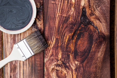 A worker applies a protective wood stain with a brush. The process of protecting and coating wooden boards. The process of restoring parquet flooring.の写真素材