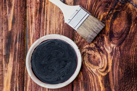 A worker applies a protective wood stain with a brush. The process of protecting and coating wooden boards.の写真素材
