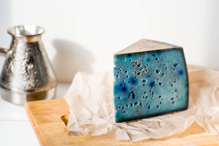 Fresh farm products. A piece of blue and yellow, fresh, aged, natural farm cheese with lavender on a wooden board.の写真素材