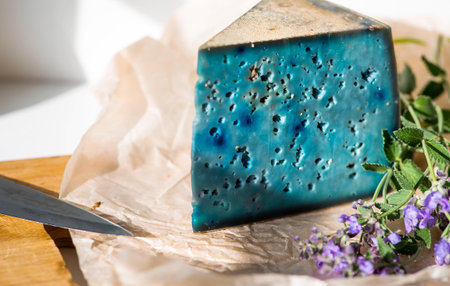 The unusual taste and quality of fresh farm products. A piece of blue, fresh, aged, natural farm cheese with lavender on a wooden board.の写真素材