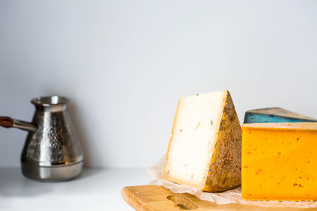 Unusual taste and quality of fresh farm products. Pieces of different fresh, aged, natural farm cheese in parchment paper on a wooden board.の写真素材
