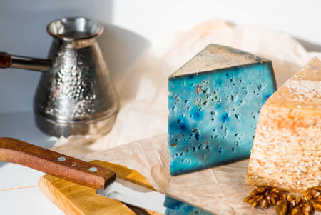 Fresh farm products. A piece of blue and yellow, fresh, aged, natural farm cheese with lavender and nuts on a wooden board.の写真素材