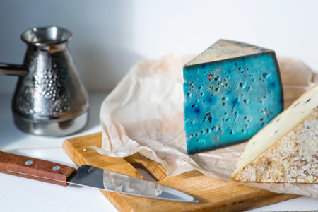 Fresh farm products. A piece of blue and yellow, fresh, aged, natural farm cheese with lavender and nuts on a wooden board.の写真素材