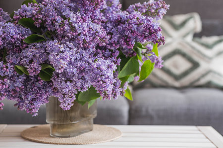 The concept of spring, home comfort, and celebration. A large purple bouquet of lilacs on the table. In the background, the interior of a modern living room.の写真素材