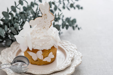 Easter cake with a white rabbit and butterflies and eucalyptus branches on a white kitchen table. Stylish Easter still life. Happy Easter 2026.の写真素材