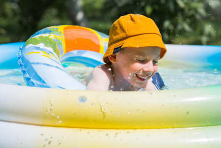 It's a hot day. A cute boy is swimming in the pool. A happy little boy is smiling at the camera. The concept of summer vacations with children.の写真素材
