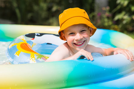 It's a hot day. A cute boy is swimming in the pool. A happy little boy is smiling at the camera. The concept of summer vacations with children.の写真素材