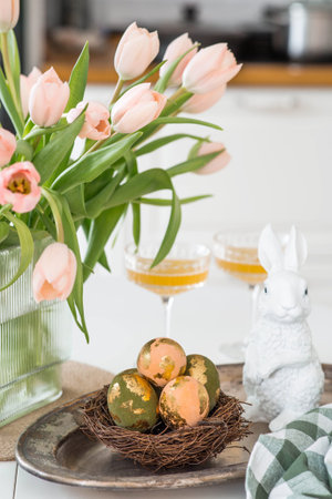 Beautiful Easter greeting card. A bouquet of delicate tulips, Easter bunnies, and golden-patterned...