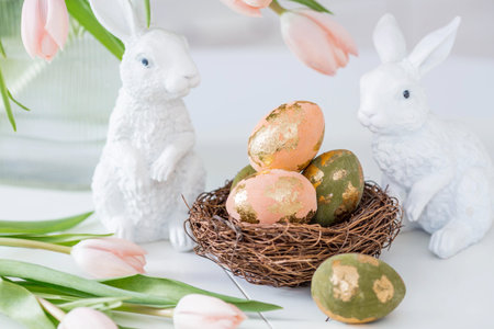 Beautiful Easter greeting card. A bouquet of delicate tulips, Easter bunnies, and golden-patterned...