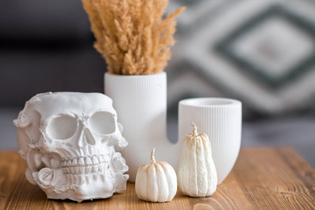 A white skull, candles and pumpkins on the table. Decor for the Day of the Dead or Halloween in the living room interior.Halloween celebration.の写真素材