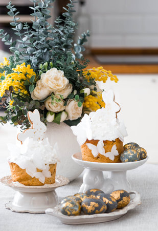 Happy Easter 2026. Easter cake with white rabbit and butterflies, Easter eggs with gold, candles and...