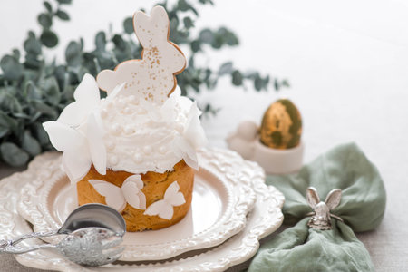 Easter cake with a white rabbit and butterflies and eucalyptus branches on a white kitchen table. Happy Easter 2026. Stylish Easter still life.の写真素材