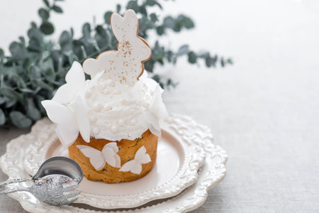 Easter cake with a white rabbit and butterflies and eucalyptus branches on a white kitchen table....