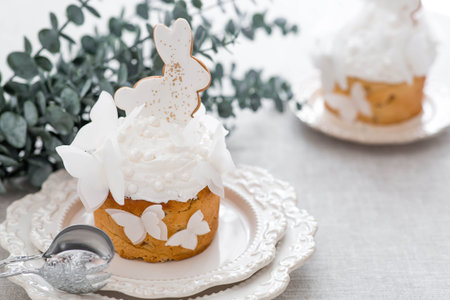 Easter cake with a white rabbit and butterflies and eucalyptus branches on a white kitchen table....