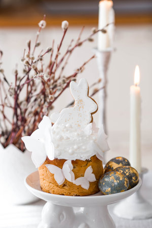 Happy Easter 2026. Easter cake with white rabbit and butterflies, Easter eggs with gold, candles and...