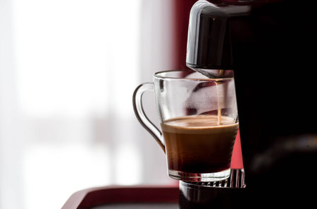 Freshly brewed coffee pouring from a coffee machine on a blurred background. The coffee maker pours...