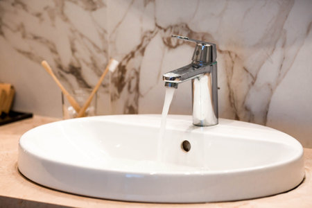 Modern bathroom interior with marble tiles, a sink, and a faucet. Sanitary store concept. Bathroom...