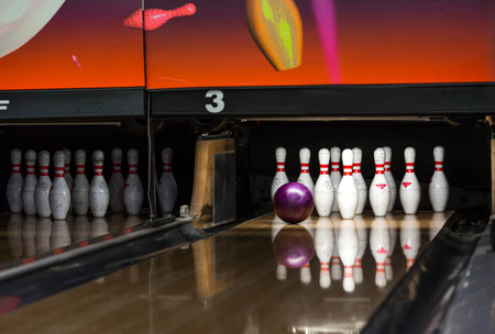 A bowling club with colorful balls and pins for bowling. The moment when a ball hits the pins in...