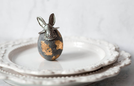 Easter eggs in gray and golden tones on a serving plate and an Easter bunny. The concept of the...