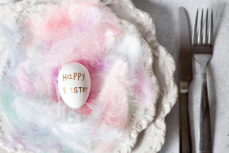 Easter eggs in gray and golden tones and light, airy feathers on a serving plate. The concept of a...