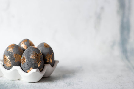 Easter eggs in gray and golden tones and an Easter bunny. The concept of the bright Easter holiday.