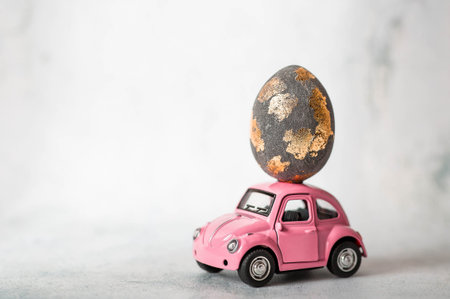 Minimalism. Pink retro car with an Easter egg on the roof. Concept of the bright Easter holiday 2026.の写真素材