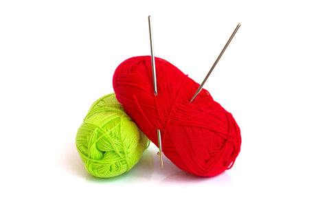 The photo shows two skeins of yarn. In a skein of yarn of red color hooks for knitting are stuck.