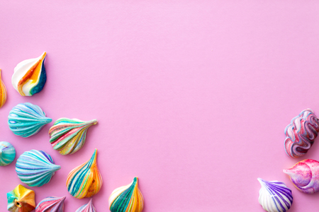 Background of colorful meringue cakes on a pink basis. Appetizing meringues. View from above. The location is in the right and left lower corners.の写真素材