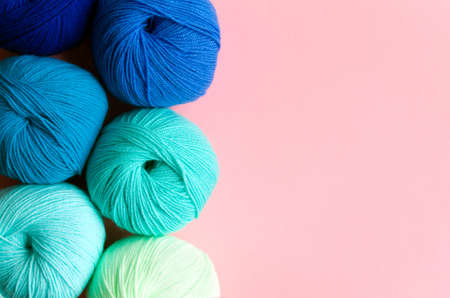 Acrylic balls of yarn in blue-green shades on a pink background. Nuance color combination. Skeins are located vertically on the left.の写真素材