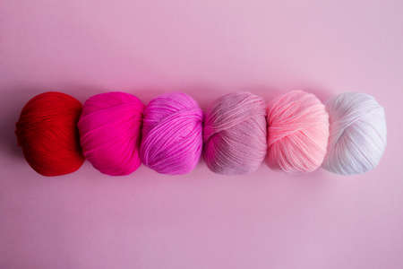 Acrylic balls of yarn on a pink background. A nuanced combination of colors. The skeins are grouped in one row.の写真素材