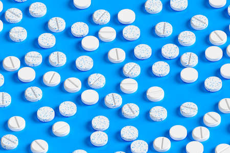 Background from white pills on a blue surface. Production of drugs. Medical theme. 3d rendering.の写真素材