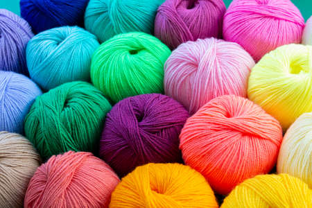 Colorful multicolored background from skeins of acrylic yarn. textile industry. Arranged balls of yarn. natural and neon colors.の写真素材