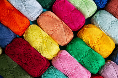 Background of multi-colored skeins of cotton yarn folded diagonally in a row. view from above....