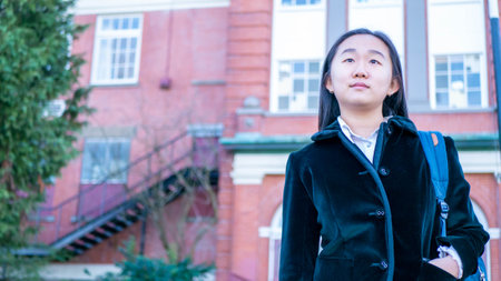 Schoolgirls looking to the future in front of the school buildingの写真素材