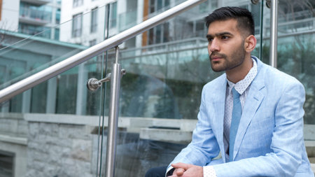Middle Eastern businessman sitting on stairs looking to the future