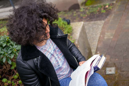 A man and a college student reading a book near a treeの写真素材