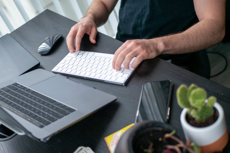 Cactus in front with man's hand typing keyboard toward desk