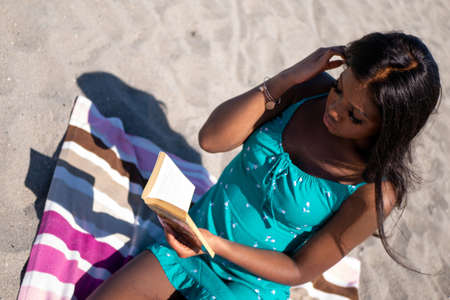 Black Canadians sitting on a sandy beach in Canada readingの写真素材