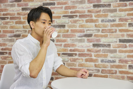 Asian male customer having a drink in cafÃ©