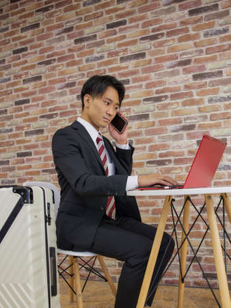 Businessman calling in cafÃ© with carry caseの写真素材