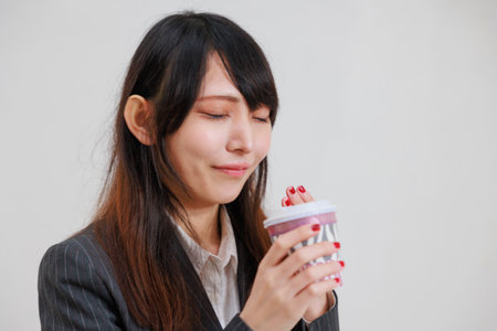 Asian woman in a suit drinking hot drinksの写真素材
