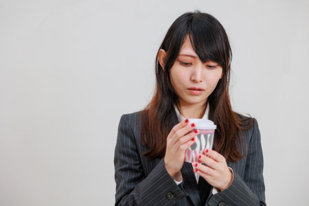 Asian woman in a suit drinking hot drinksの写真素材
