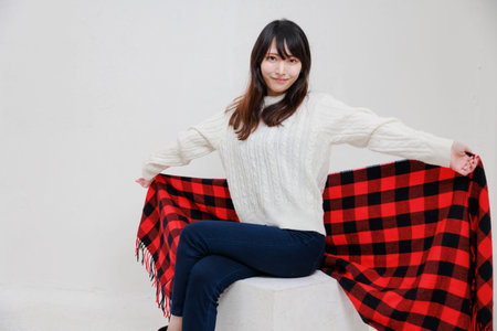 Beautiful asian woman sitting in white box in front of white backgroundの写真素材