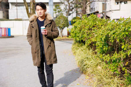 young asian man with coffee cup in the park, lifestyle people conceptの写真素材