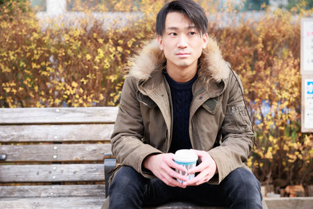 young asian man drinking coffee in the park, lifestyle concept.の写真素材
